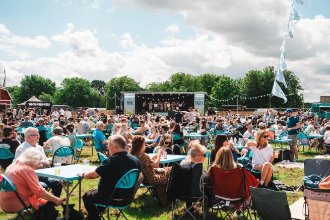 We're focused on a snapshot of a Food & Drink Festival where festival goers are lounged on furniture watching the live entertainment and enjoying delicious food!