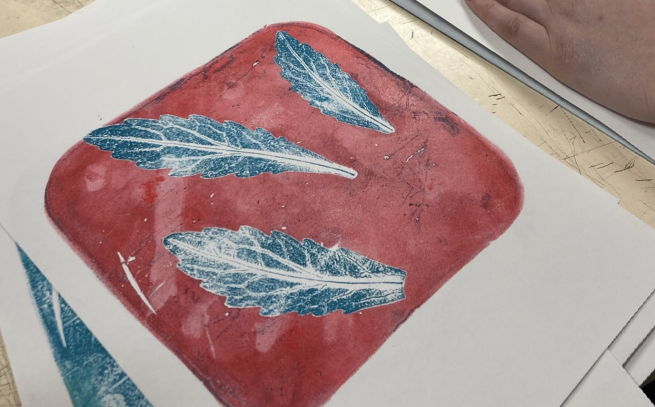 A gelli printed image of blue leaves on a red background