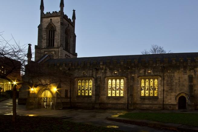 St John's church, a 17th Century building, at twilight. Lights glow from the windows.