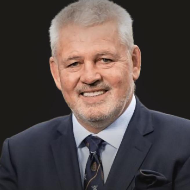 Warren Gatland in a suit and patterned tie smiling.