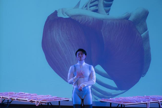 Artist standing in front of a projected artwork, all in shades of blue