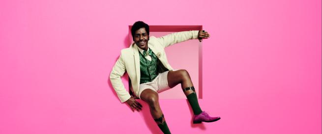 A man sitting in a cutout of a bright pink wall.