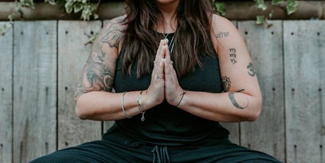 Yoga Teacher Amy Thwaites sitting in meditation and hands in prayer position