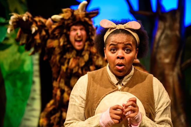 A woman dressed as a mouse looks scared, while an actor dressed as the Gruffalo has a scary face behind her