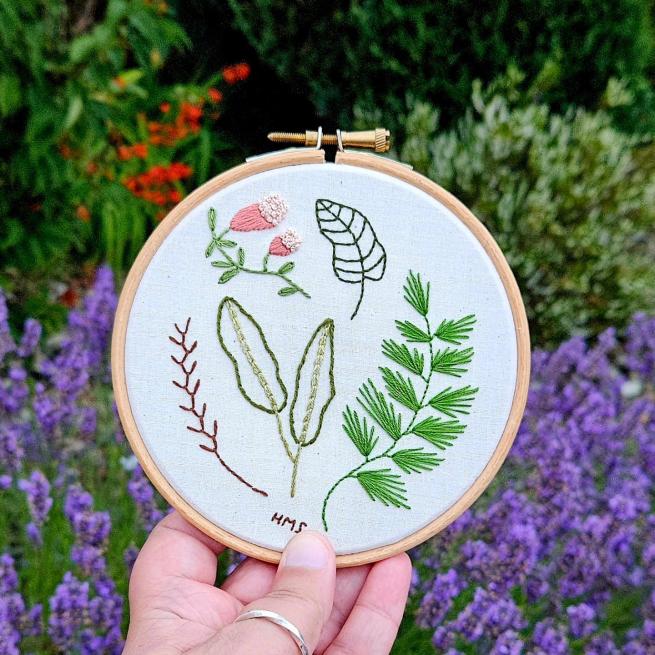 Embroidery hoop with botanicals and leaves stitched into it.