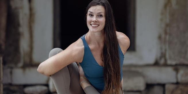 Yoga teacher Jess in a seated pose with her right arm bound around her right leg