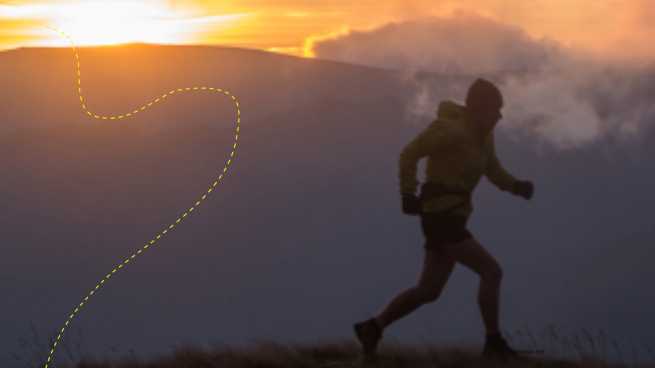 A sihouetted runner with frosty breath and the sun low behind a mountain