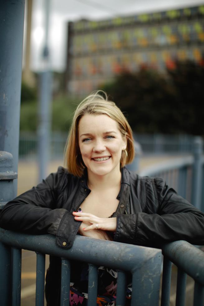 Author Rachel Bower leaning on metal railings looking towards the camera