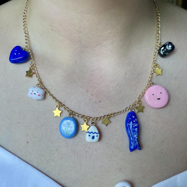 a photo of a gold necklace with a selection of poly clay charms dangling from it