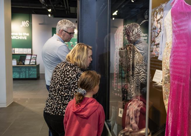 Three people look into an exhibition case