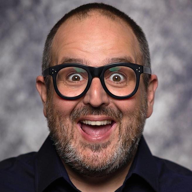 A headshot of Justin Moorhouse smiling.