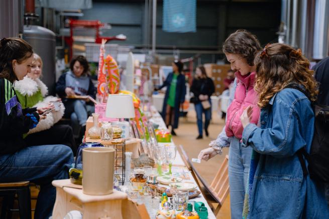 An image inside Mindful Market, shoppers are browsing a pop-up stall that sells seconf-hand and vintage wares.