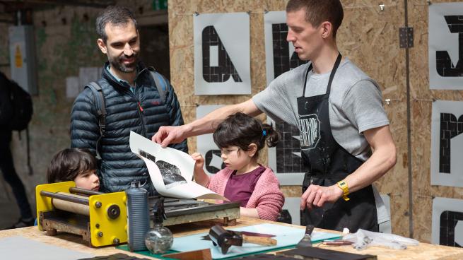 people gather around a table to partake in a printing workshop