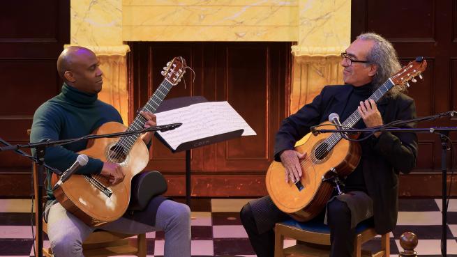 Eduardo and Ahmed sat down playing their guitars.