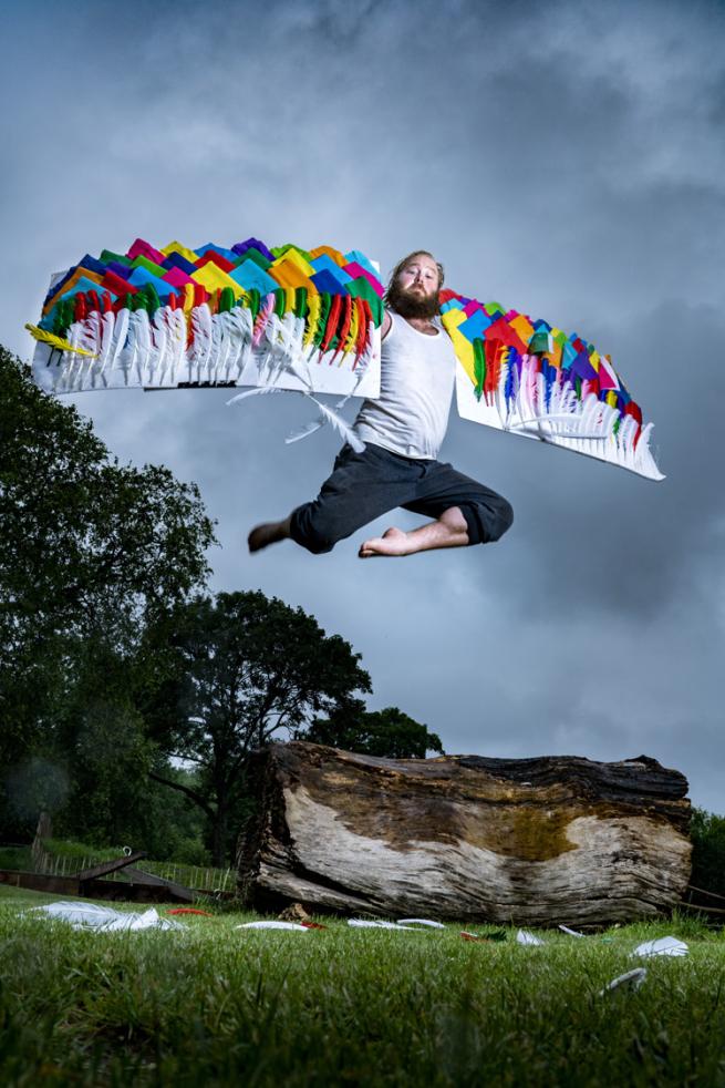 James Rowland jumping in the air with homemade wings on his arms.