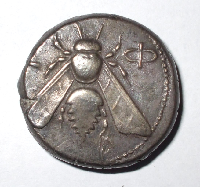 Small silver coin with a bee on the surface. 