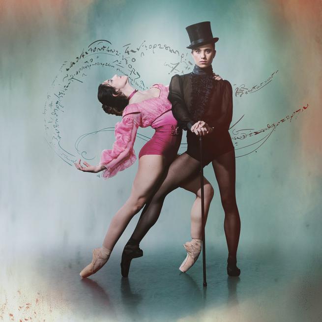 A ballerina in black with a cane and a top hat with another ballerina in pink on pointe with an arched back.