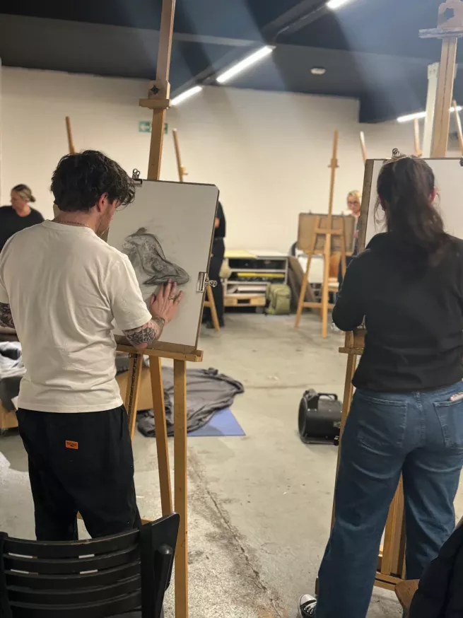 point of view of artists stood at easels drawing the life model