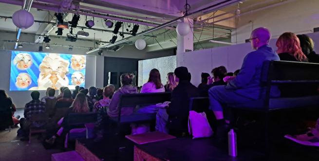 A room of people facing a cinema screen in the dark