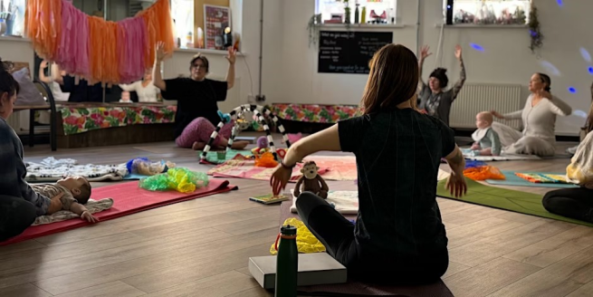 A group of parents seated on the floor with their babies