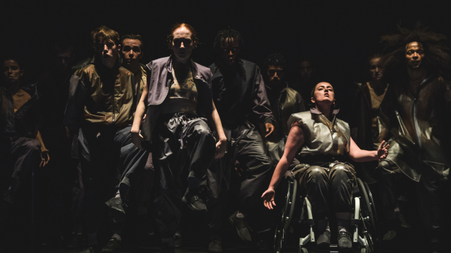 Performers are dancing on stage. One performer is in a wheelchair.