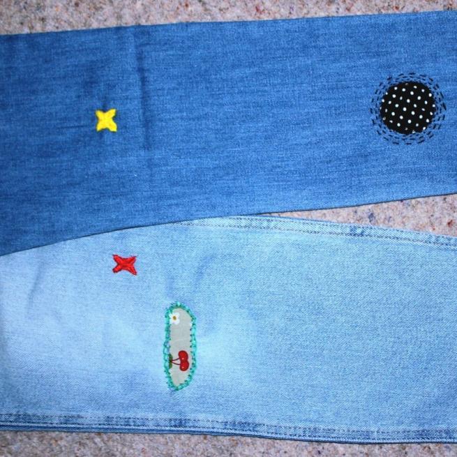 A photograph of a pair of blue jeans with different stitched patches on them.