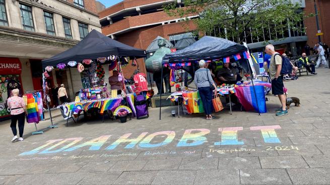 Photo showing stalls from 2024 with IDAHOBIT chalked on the ground