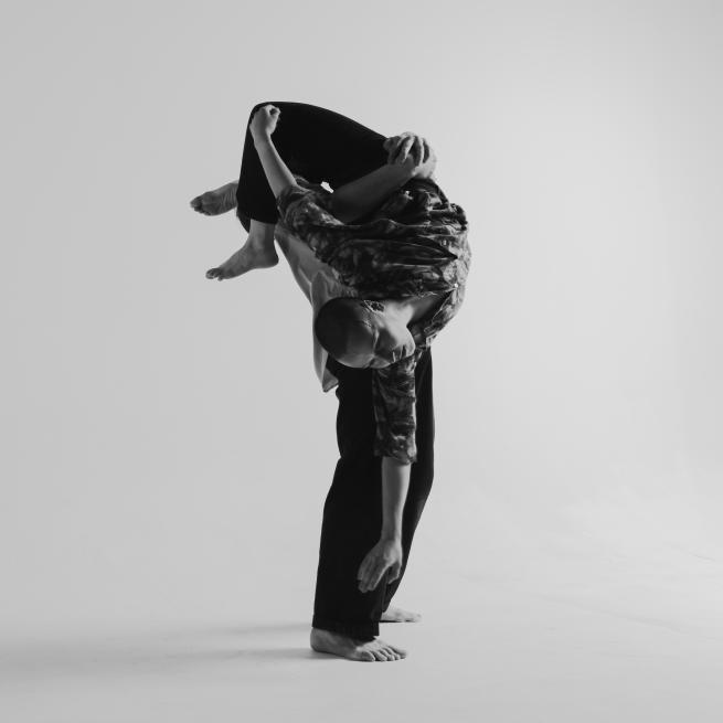 Black and white image of dancer being help upside down