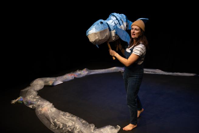 Woman holding whale puppet performing.
