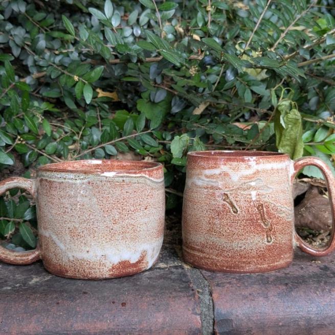Photo of two brown glazed mugs.
