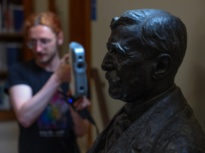 A photo of someone pointing imaging equipment at a dark bust sculpture.