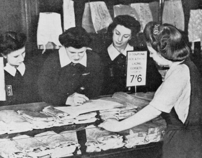 black and white photograph of women working at a shop counter