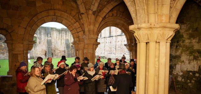 An image of the Heritage Singers in the Abbey's Chapter House singing carols