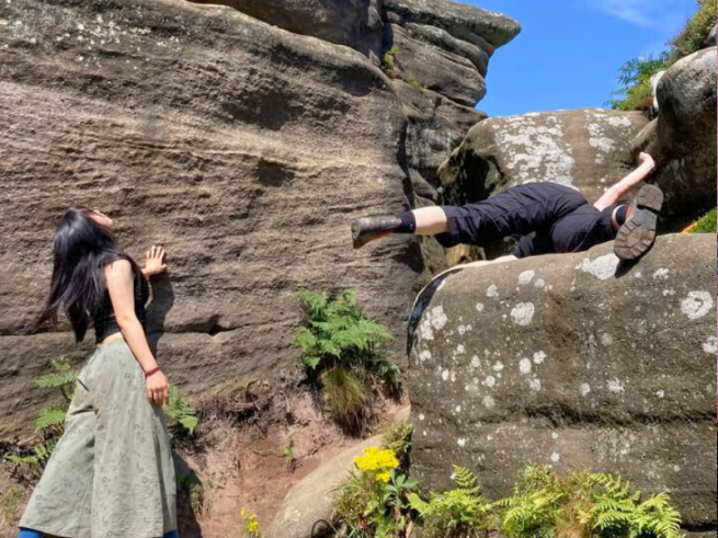 Two women climbing up Brimham Rocks