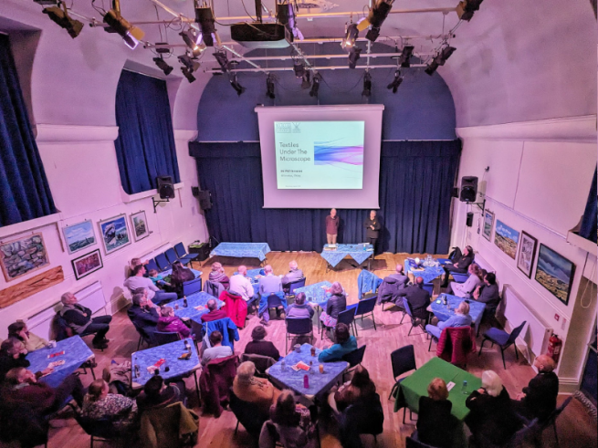 People sat in a hall watching a powerpoint about biology.