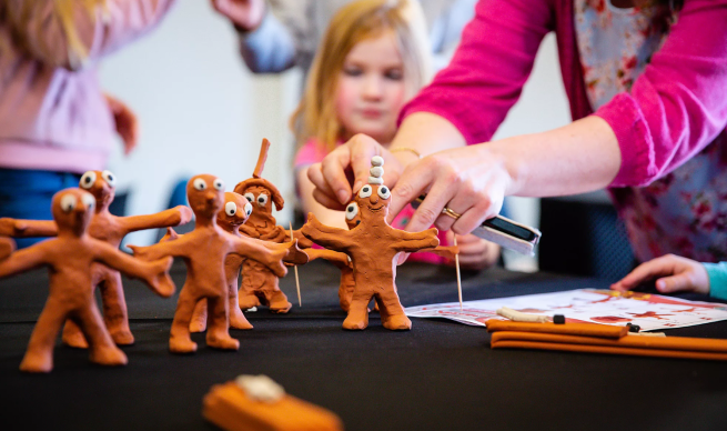 Multiple of the same orange human-like figure and someone touching one of them