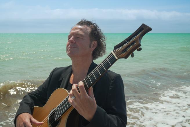 Richard Durrant with his bog oak guitar by the sea