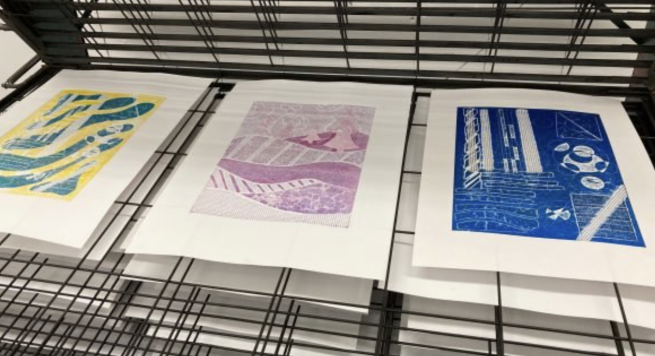 A selection of abstract collograph prints in multiple colours drying on a drying rack