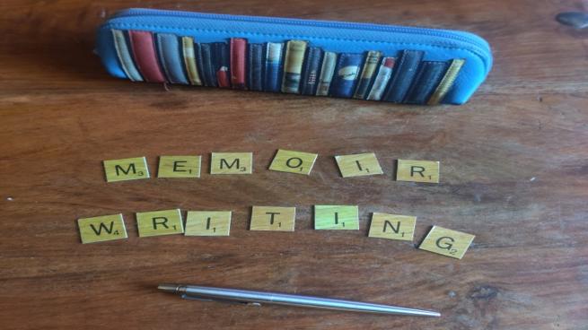 A photo of a pencil case and scrabble letters forming the words "Memoir Writing"