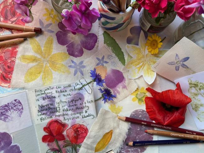 Craft table during a flower pressing workshop with flowers, pencils, cloth and paint.