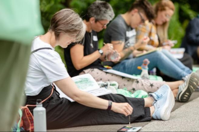 four artists, seated, drawing and painting