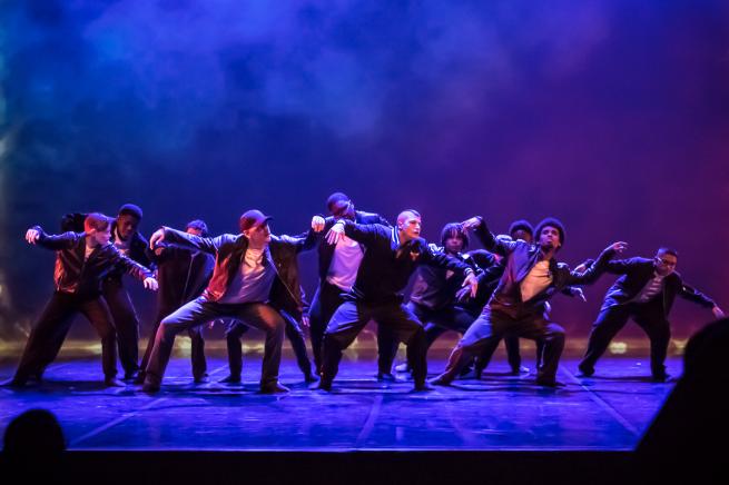 Group of 10 boys in black and white dancing on a stage
