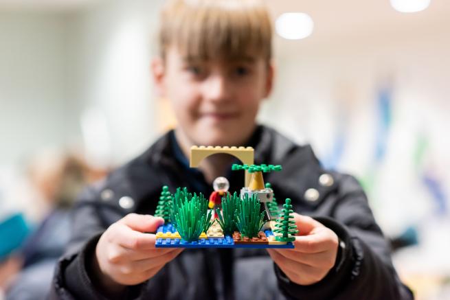 A young boy holding up a LEGO creation