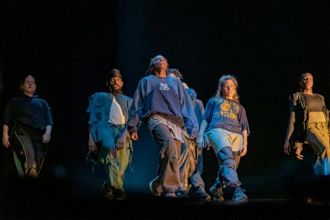 Group of dancers facing forward photographed from below stage