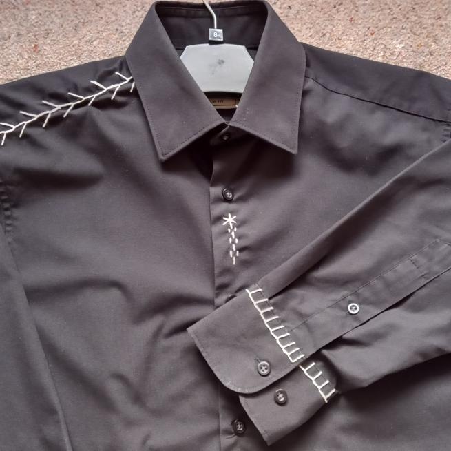 A photograph of a black shirt with white stitching detail