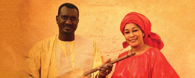 A man holding a stringed musical instrument next to a woman smiling.