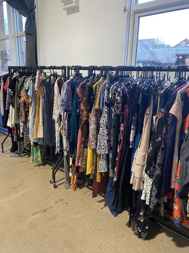 Rails of colourful clothing in a brightly lit room