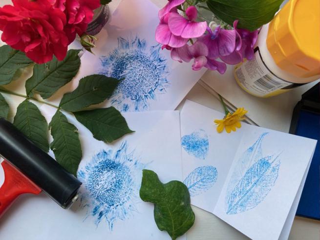 Craft table with different plants, paint roller and ink.