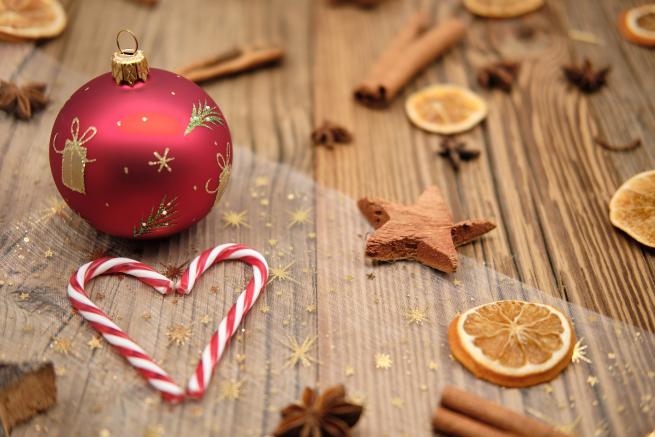 Table with Christmas decor on, including a red bauble, candy canes, and dried fruit and cinnamon