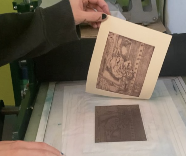 An etched print being revealed from the printing plate